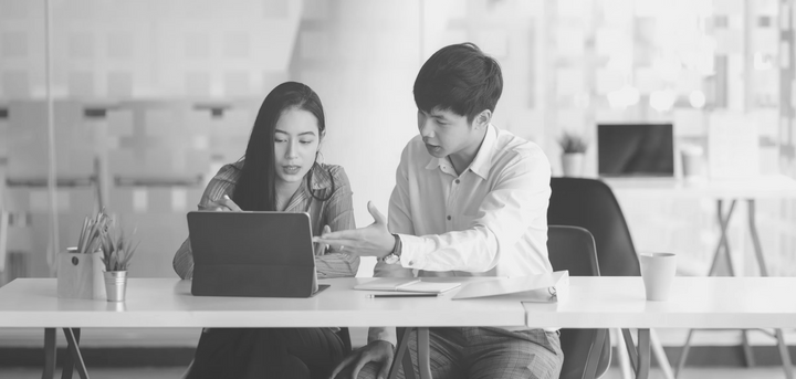 a woman and man sitting at a table with a laptop